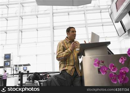 Mid adult man with a laptop looking surprised at an airport