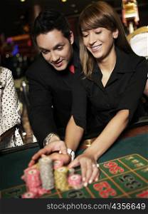 Mid adult man with a young woman placing gambling chips on a gambling table