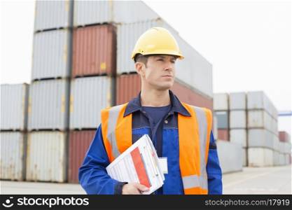 Mid adult man with clipboard in shipping yard