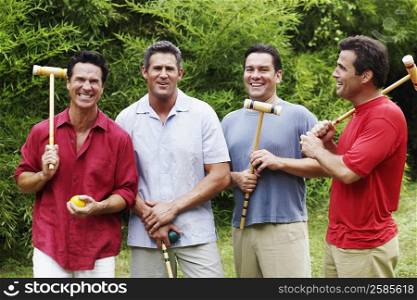 Mid adult man with three mature men holding croquet mallets and balls