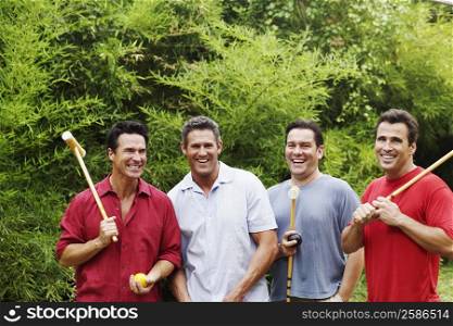 Mid adult man with three mature men holding croquet mallets and smiling