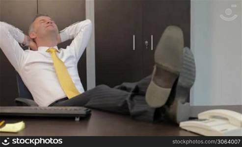 Mid- adult manager relaxing at work with feet on desk