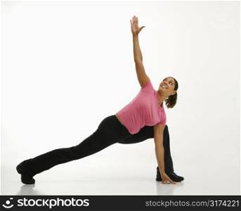 Mid adult multiethnic woman wearing exercise clothing holding yoga pose and smiling.