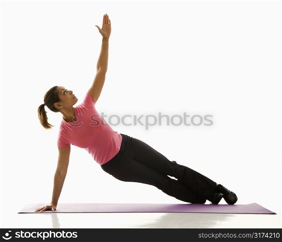 Mid adult multiethnic woman wearing exercise clothing holding yoga pose and stretching.