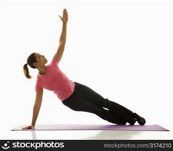 Mid adult multiethnic woman wearing exercise clothing holding yoga pose and stretching.