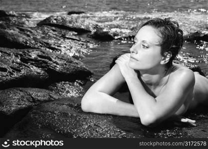 Mid adult nude Caucasian woman lying on stomach in water at Maui, Hawaii beach.