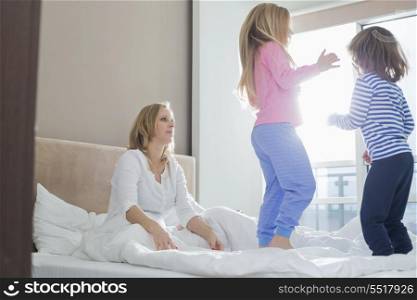 Mid adult parents looking at playful children in bedroom