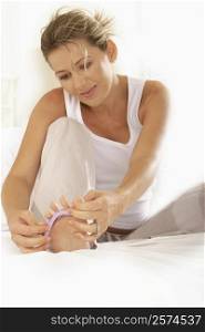 Mid adult woman adjusting her toenail divider