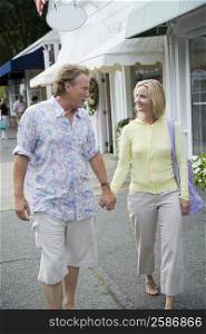 Mid adult woman and a mature man holding hands and walking