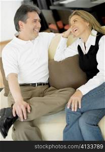 Mid adult woman and a mature man sitting on a couch and looking at each other