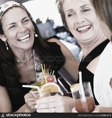 Mid adult woman and a mature woman holding glasses of cocktail and smiling