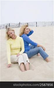 Mid adult woman and a mature woman sitting on the beach