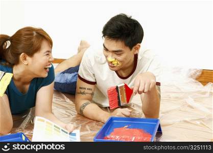 Mid adult woman and a young man holding paintbrushes and smiling