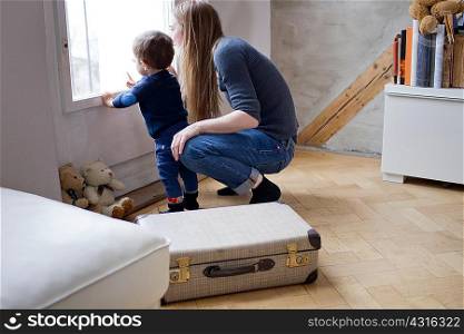 Mid adult woman and baby son pointing at window