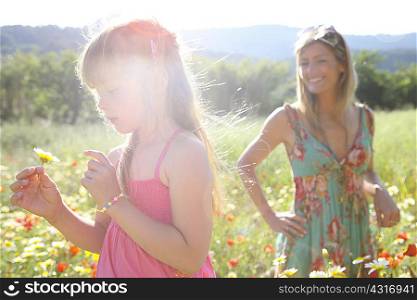 Mid adult woman and daughter picking wildflowers in meadow, Majorca, Spain