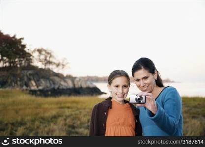 Mid adult woman and her daughter looking at a digital camera