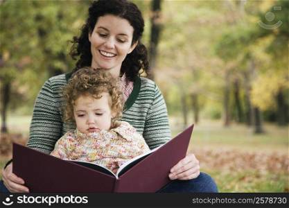 Mid adult woman and her daughter looking at a picture book
