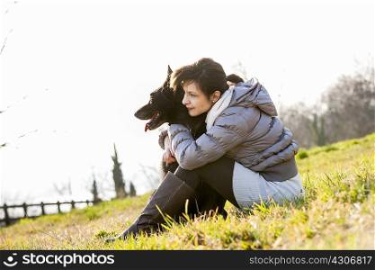 Mid adult woman and her dog sitting on hillside