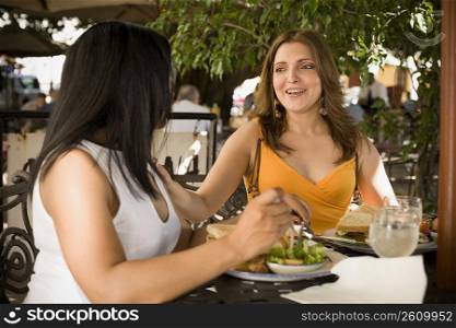 Mid adult woman and her friend sitting at a restaurant and smiling, Santo Domingo, Dominican Republic