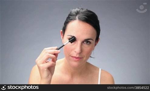 mid adult woman applying eye make-up. 30fps