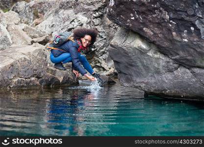 Mid adult woman crouching by pond