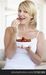 Mid Adult Woman Eating A Bowl Of Strawberries