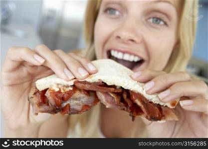 Mid Adult Woman Eating Bacon Sandwich