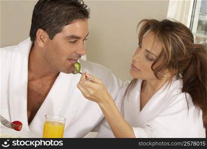 Mid adult woman feeding a mid adult man a slice of cucumber