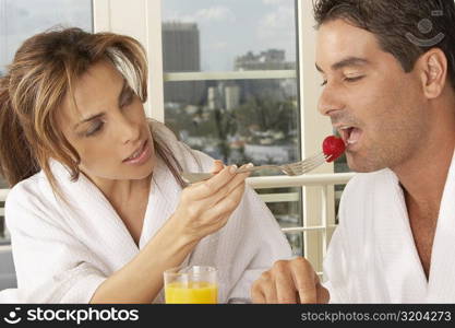Mid adult woman feeding a mid adult man a strawberry