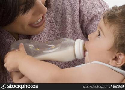 Mid adult woman feeding her son with a baby bottle and smiling
