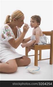 Mid adult woman feeding her son with a spoon