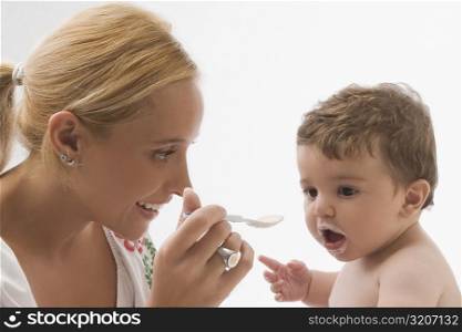Mid adult woman feeding her son with a spoon and smiling