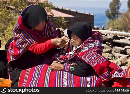 Mid adult woman grooming a bride for wedding, Taquile Island, Lake Titicaca, Puno, Peru