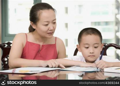 Mid adult woman helping her son in his homework