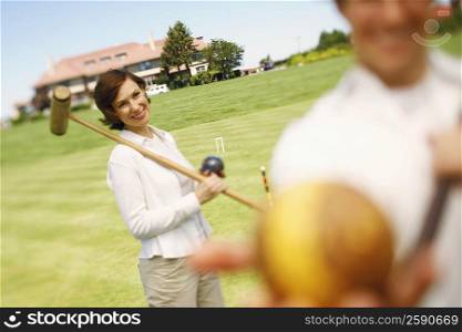 Mid adult woman holding a croquet mallet and a ball