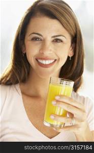 Mid Adult Woman Holding A Glass Of Orange Juice, Smiling At The Camera