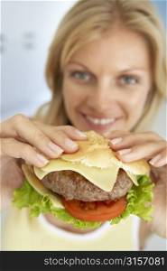 Mid Adult Woman Holding A Hamburger, Smiling At The Camera