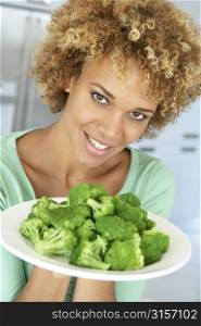 Mid Adult Woman Holding A Plate Of Broccoli, Smiling At The Camera