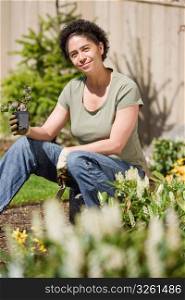 Mid adult woman holding plant in garden, portrait