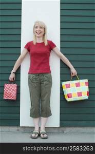 Mid adult woman holding shopping bags and smiling