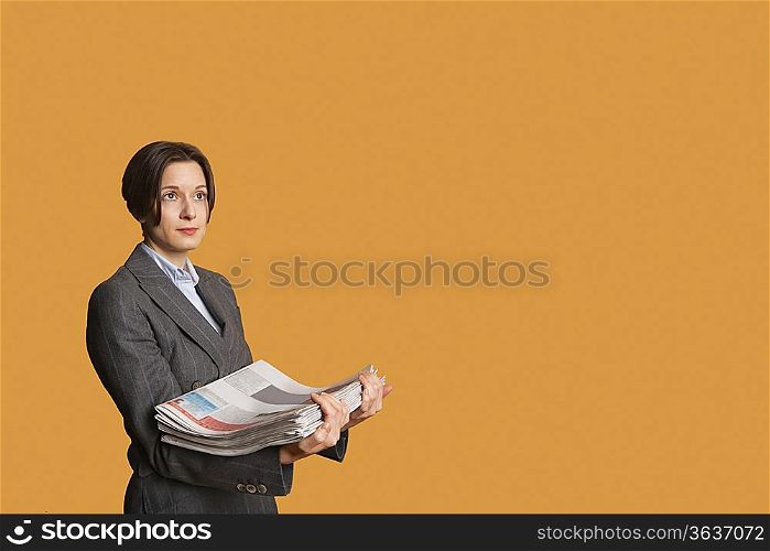 Mid adult woman holding stack of newspapers