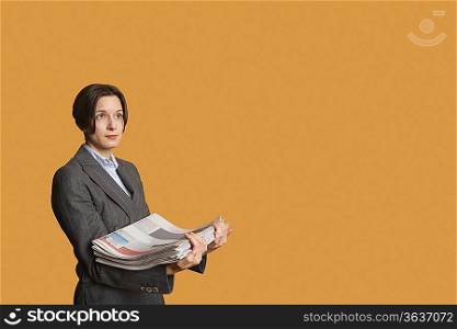 Mid adult woman holding stack of newspapers