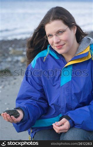 Mid adult woman holding stone at beach, portrait