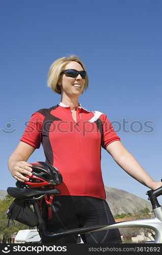 Mid adult woman in red cycling top with bike