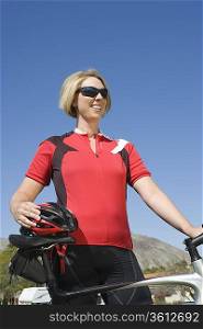 Mid adult woman in red cycling top with bike