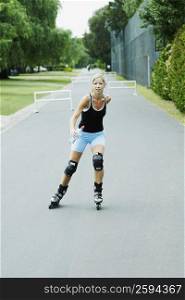 Mid adult woman inline skating and holding a water bottle