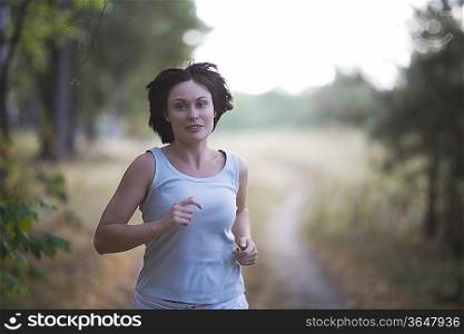 Mid adult woman jogs in woodland