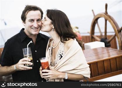 Mid adult woman kissing a mid adult man on a sailing ship