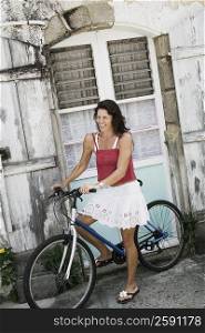 Mid adult woman learning how to ride a bicycle in front of a house