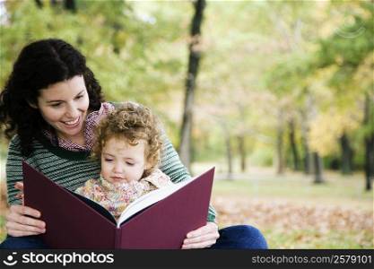 Mid adult woman looking at a picture book with her daughter